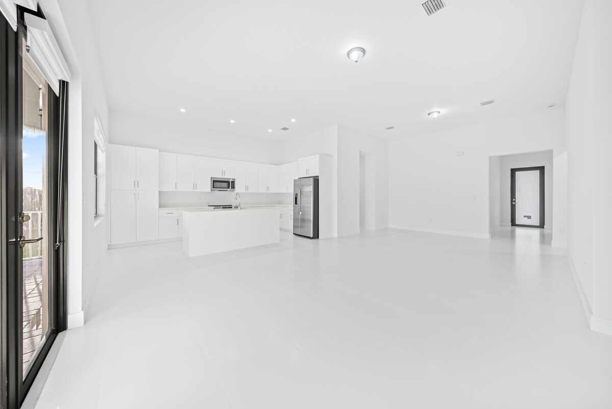 Cuisine blanche moderne et espace de vie lumineux, avec de grandes fenêtres.